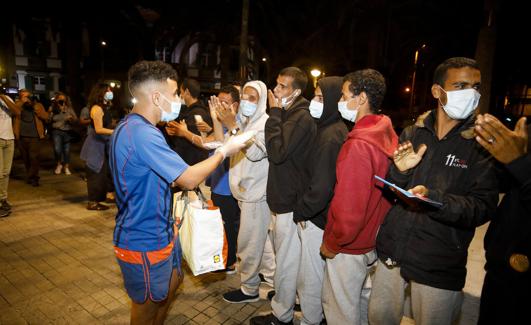 Un vecino de la capital grancanaria reparte comida a los inmigrantes que el martes fueron sacados del muelle y abandonados a su suerte.