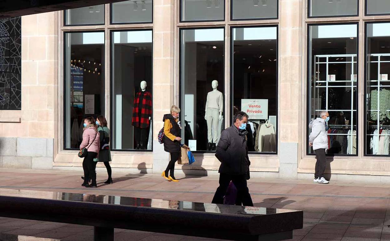 Varios ciudadanos pasean por delante de un escaparate.