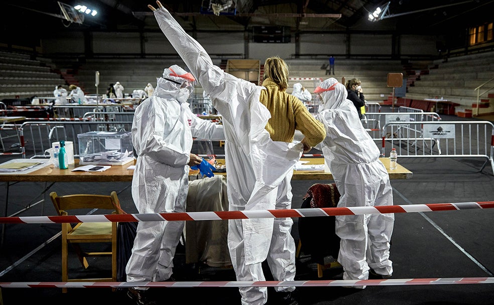 Los miembros de las mesas de votación se colocan los trajes de protección EPI durante la franja horaria de las 19.00 a las 20.00 h. en el colegio electoral de las Cotxeres de Sants, hora de votación de los que padecen Covid-19.