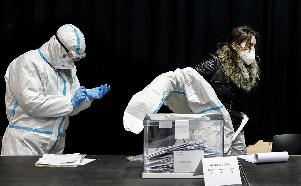 Los miembros de las mesas de votación se colocan los trajes de protección EPI durante la franja horaria de las 19.00 a las 20.00 h. en el colegio electoral de las Cotxeres de Sants, hora de votación de los que padecen Covid-19.