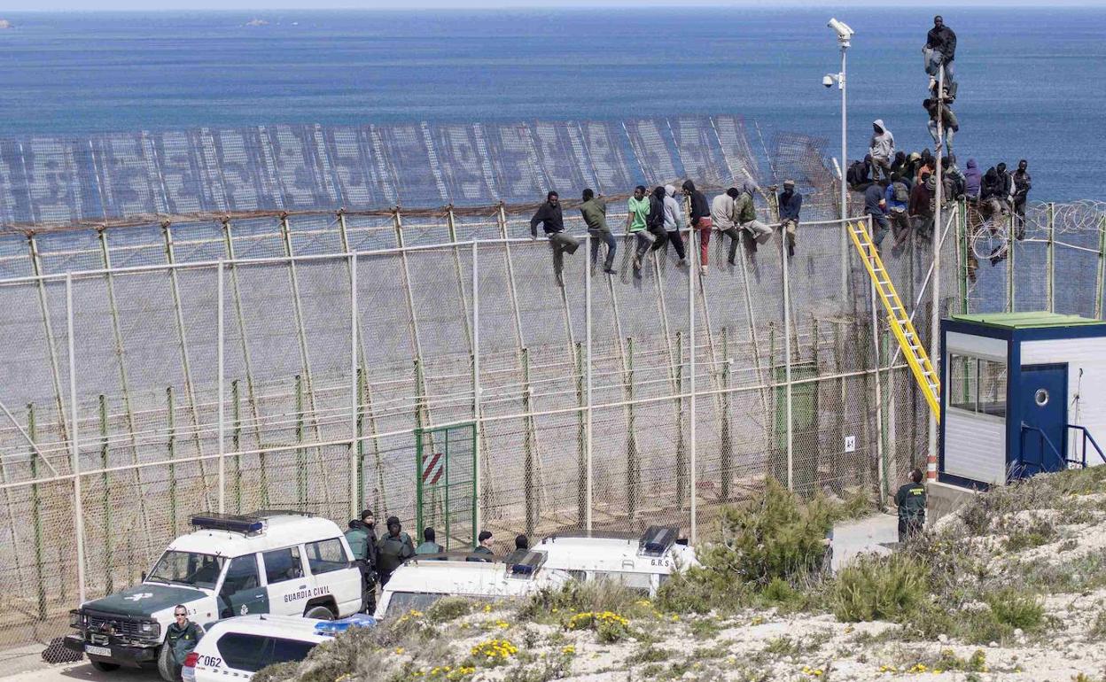 Inmigrantes encaramados a la valla de Melilla, en una imagen de archivo.