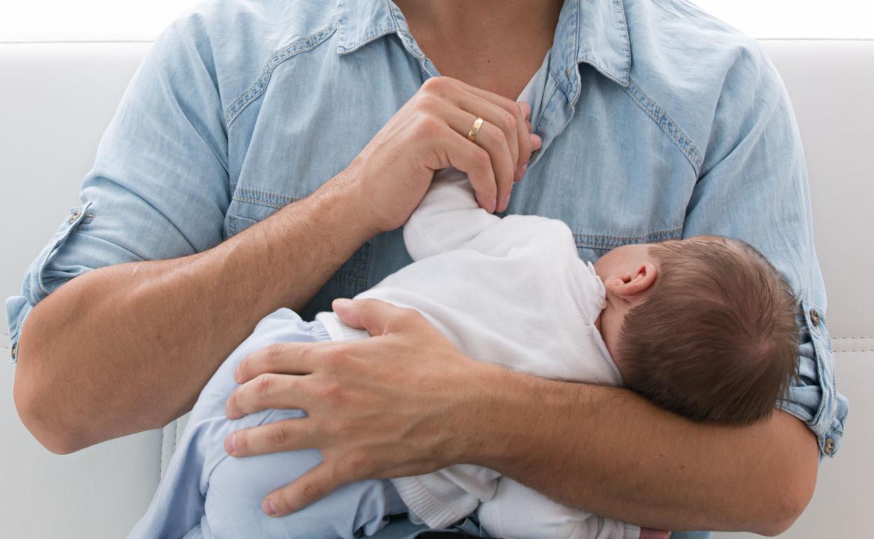 Un padre con su bebé en brazos.