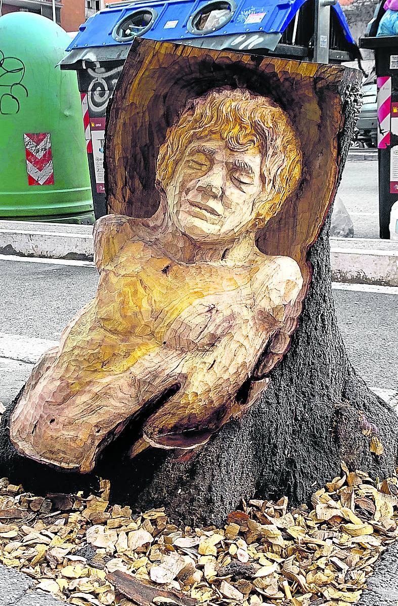 Busto esculpido en una acera del centro, sobre una cama de astillas.