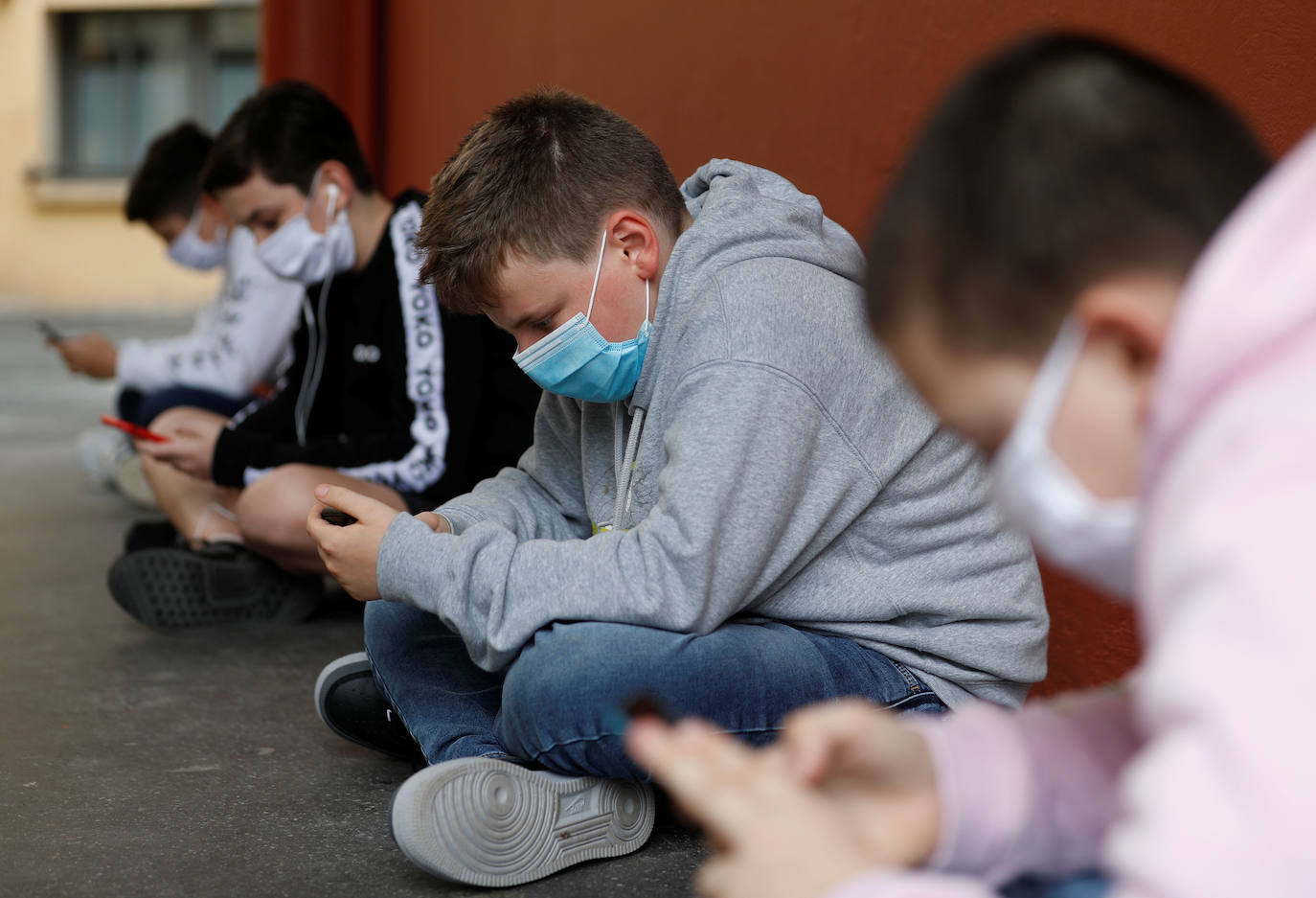 Niños usando el móvil en el recreo del colegio. 