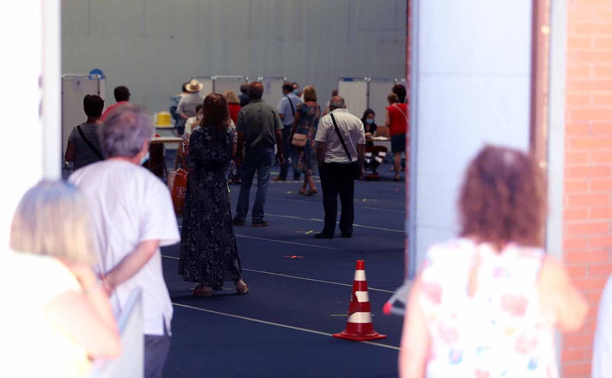 Varias personas observan desde el exterior del polideportivo de la UBU la vacunación.