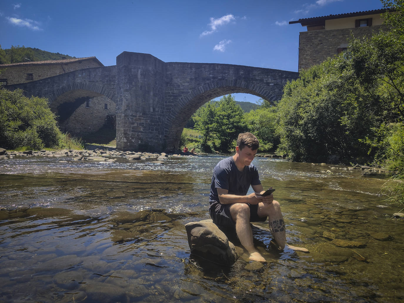 Daniel se toma un descanso junto al puente de La Rabia, en Zubiri. El agua baja fría en pleno verano y alivia los pies.