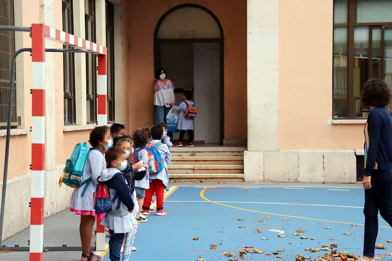 Una profesora saluda con el cole a uno de sus alumnos.