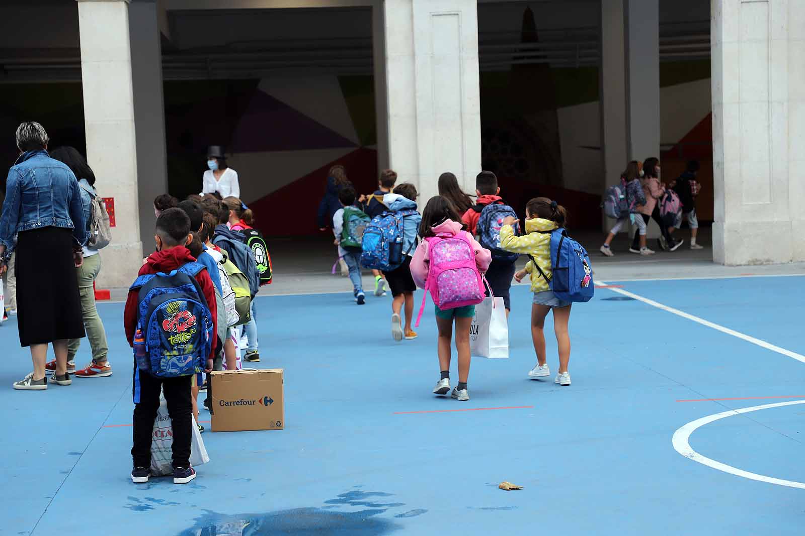 Una profesora saluda con el cole a uno de sus alumnos.