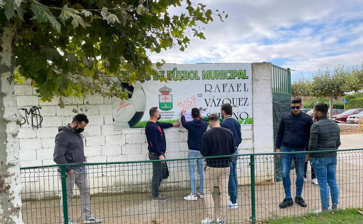 Un grupo de amigos y su hermano Carlos colocan una foto y un crespón negro, esta mañana en Villamuriel. 