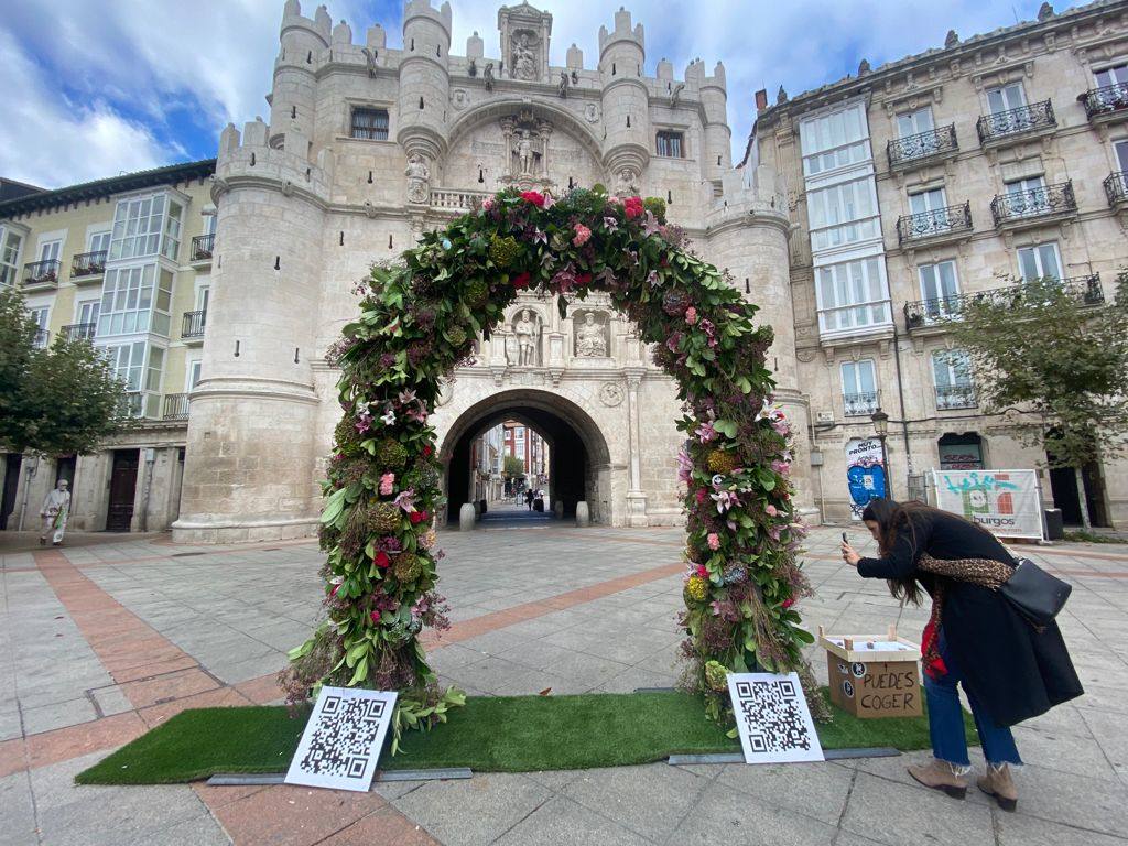 Una joven se acerca a fotografiar este arco floral en el centro de Burgos.