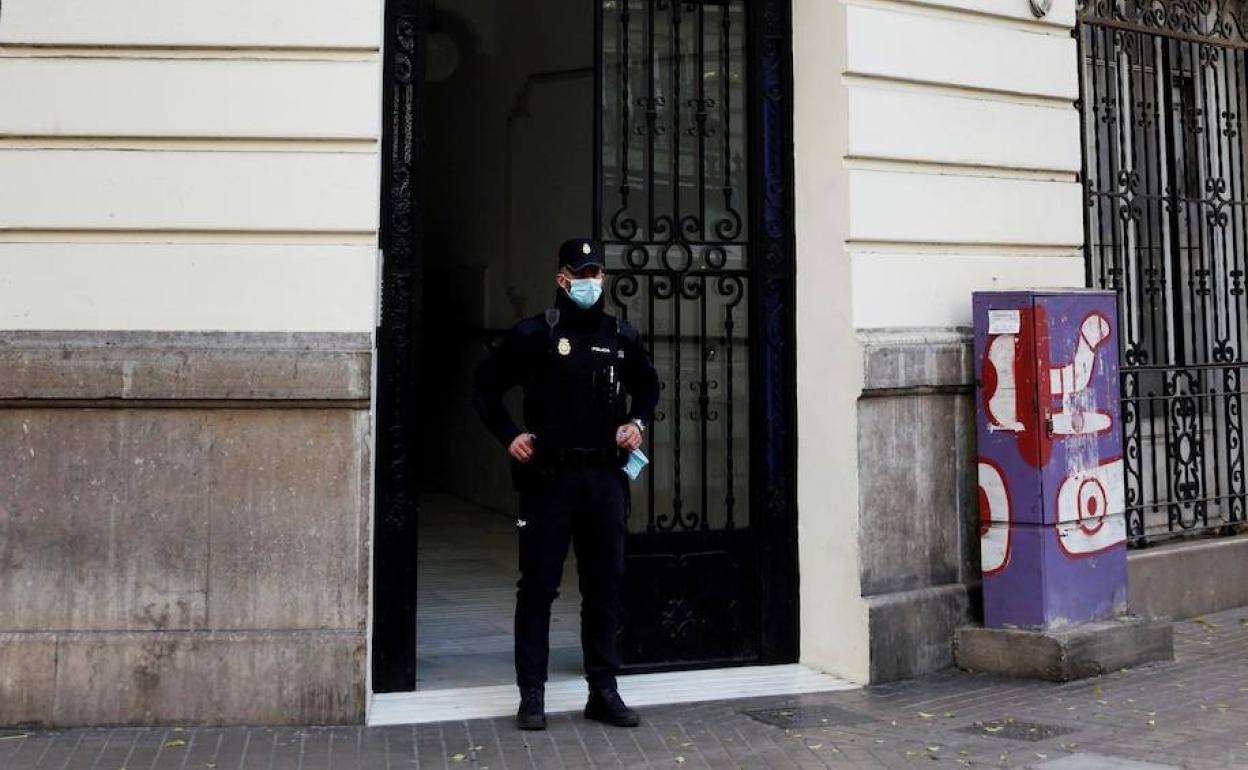 Un agente de la Policía Nacional vigila la entrada de un inmueble.