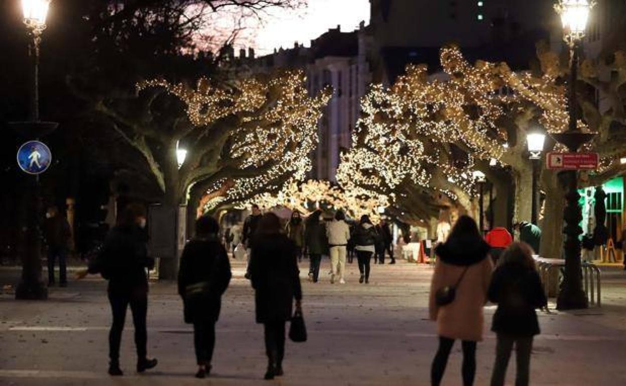 Personas paseando por el Espolón de Burgos decorado por Navidad.