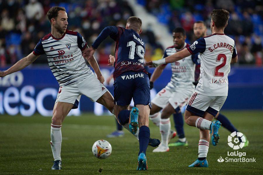 Los jugadores del Mirandés tratan de parar al jugador del Huesca.