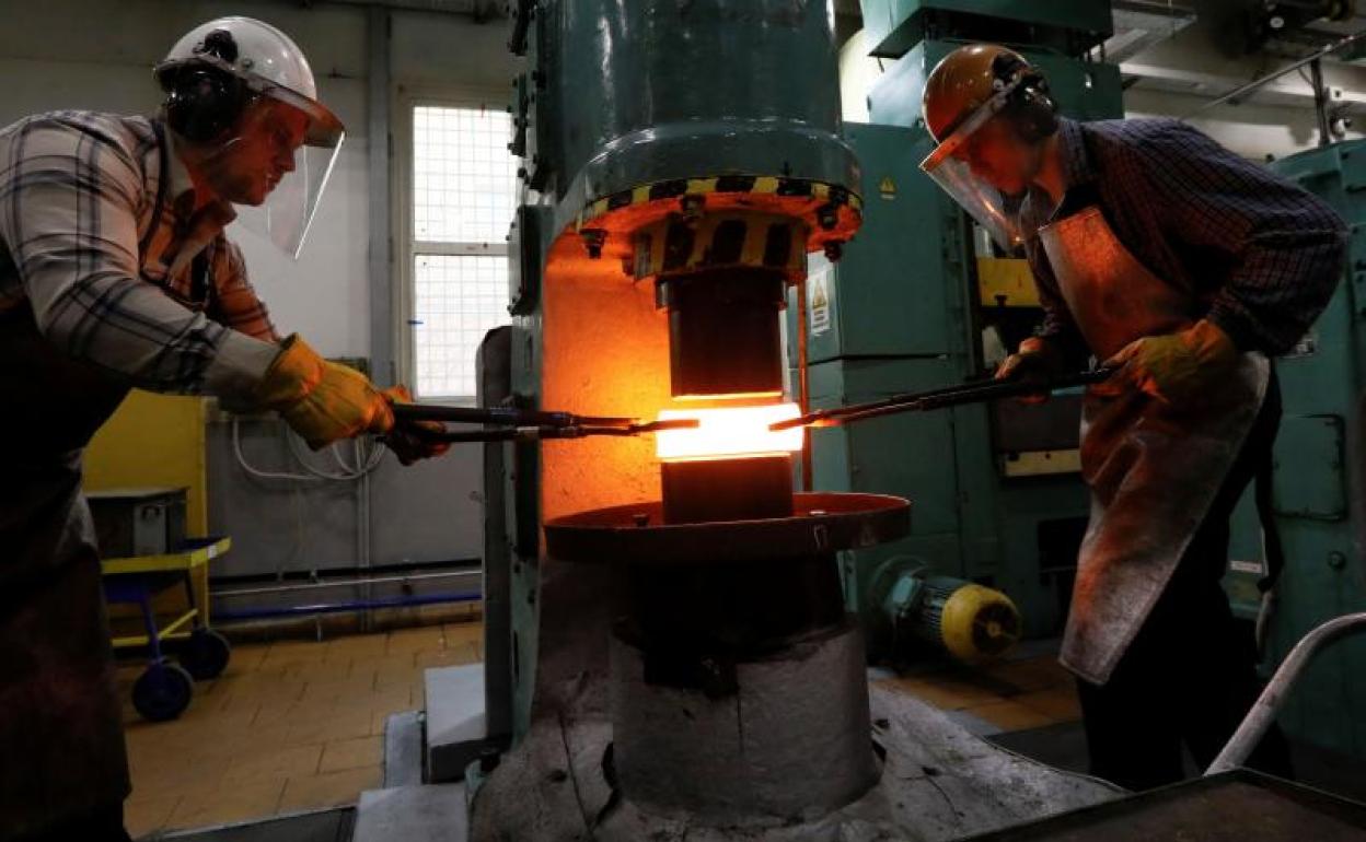 Dos trabajadores dan forma a un lingote de paladio en una planta en Krasnoyarsk.