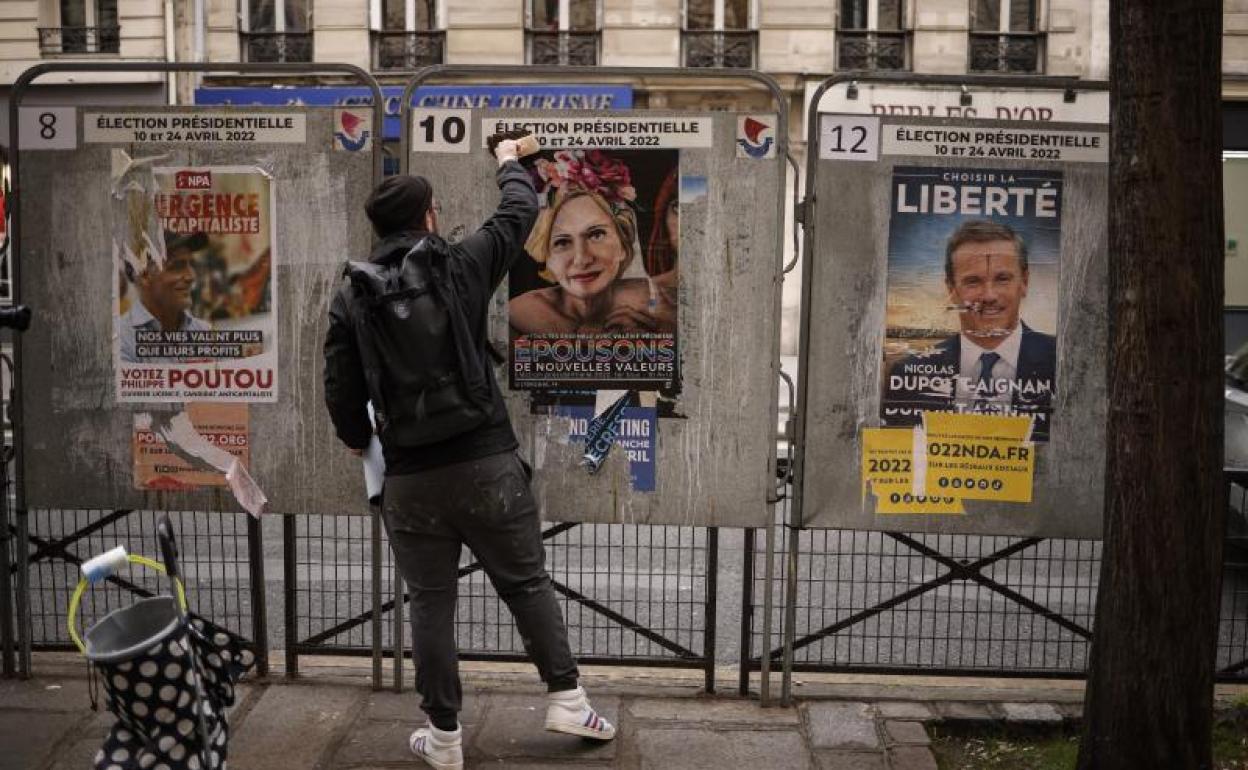 El artista callejero francés Jaeraymie pega un cartel electoral que representa una caricatura de 'Les Republicains' durante las elecciones.