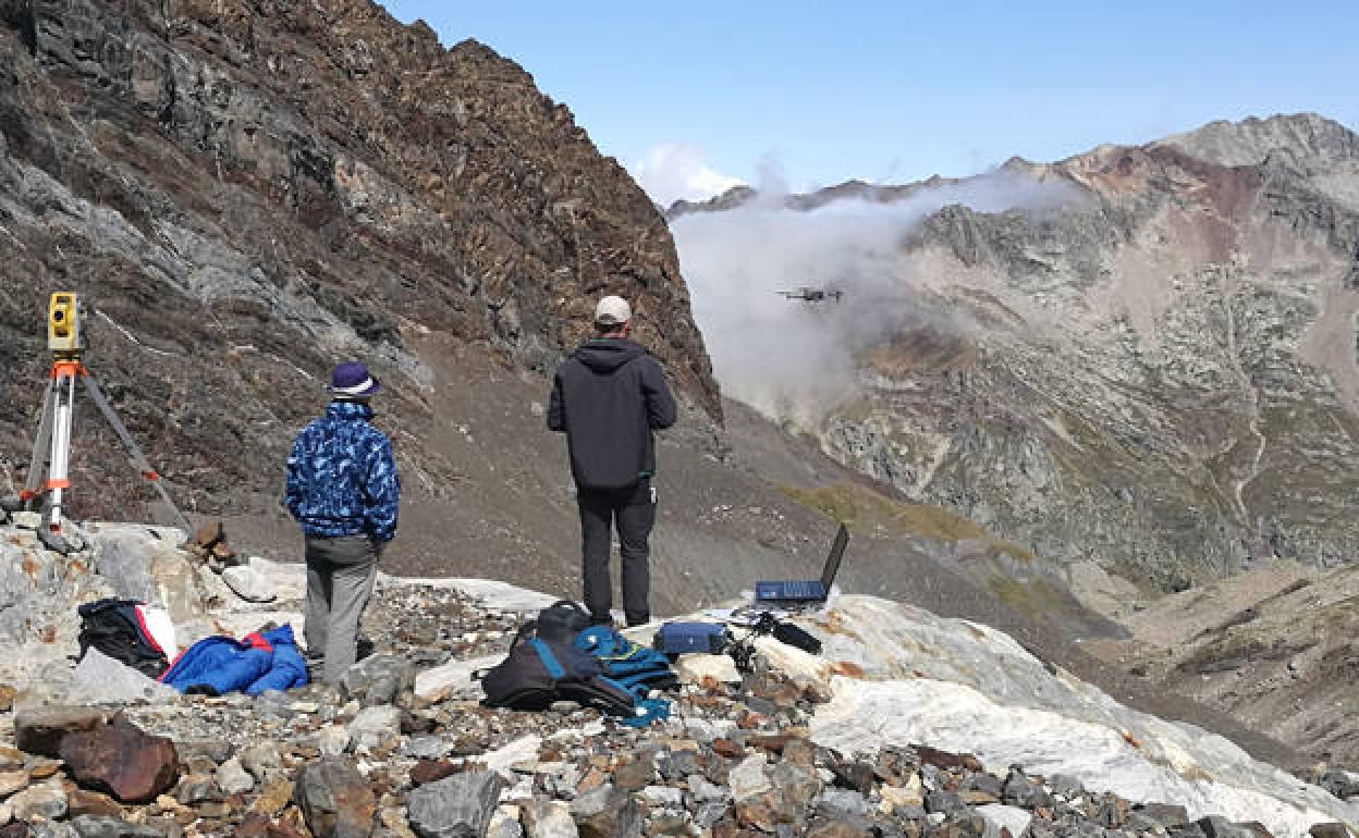 Dos investigadores controlan un dron en alta montaña. 