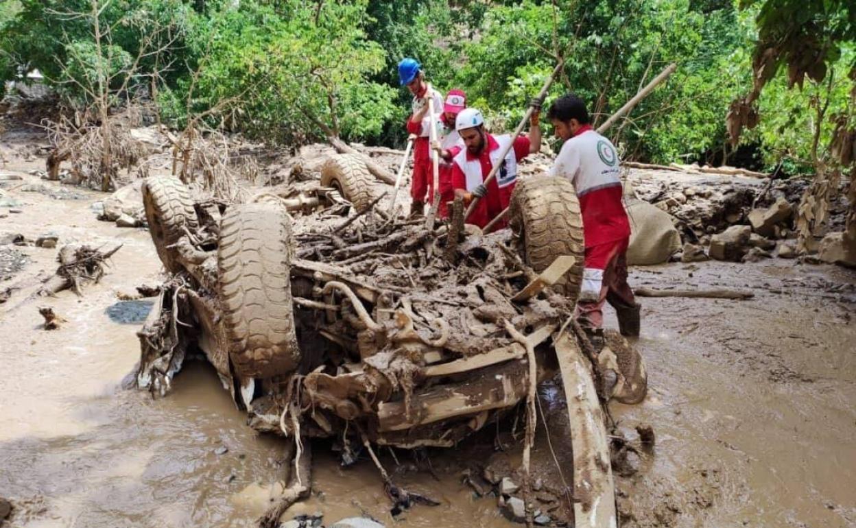 Cuatro miembros del equipo de rescate trabajan en un área dañada en la parte noroeste de Teherán por las fuertes lluvias. 