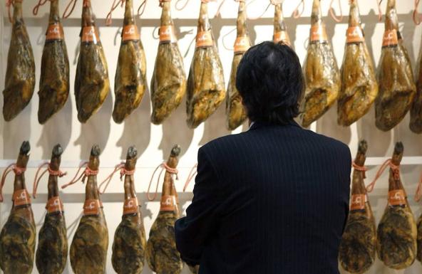 Un hombre observa los jamones ibéricos expuestos en un «stand». 