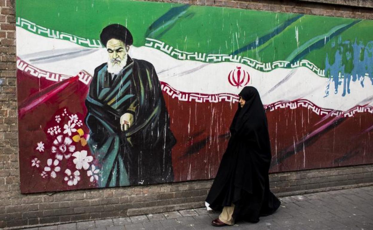 Una mujer pasa junto a un mural que conmemora la memoria de Jomeini. 