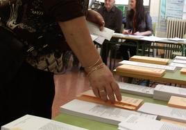 Una mujer escoge papeleta en un colegio electoral.