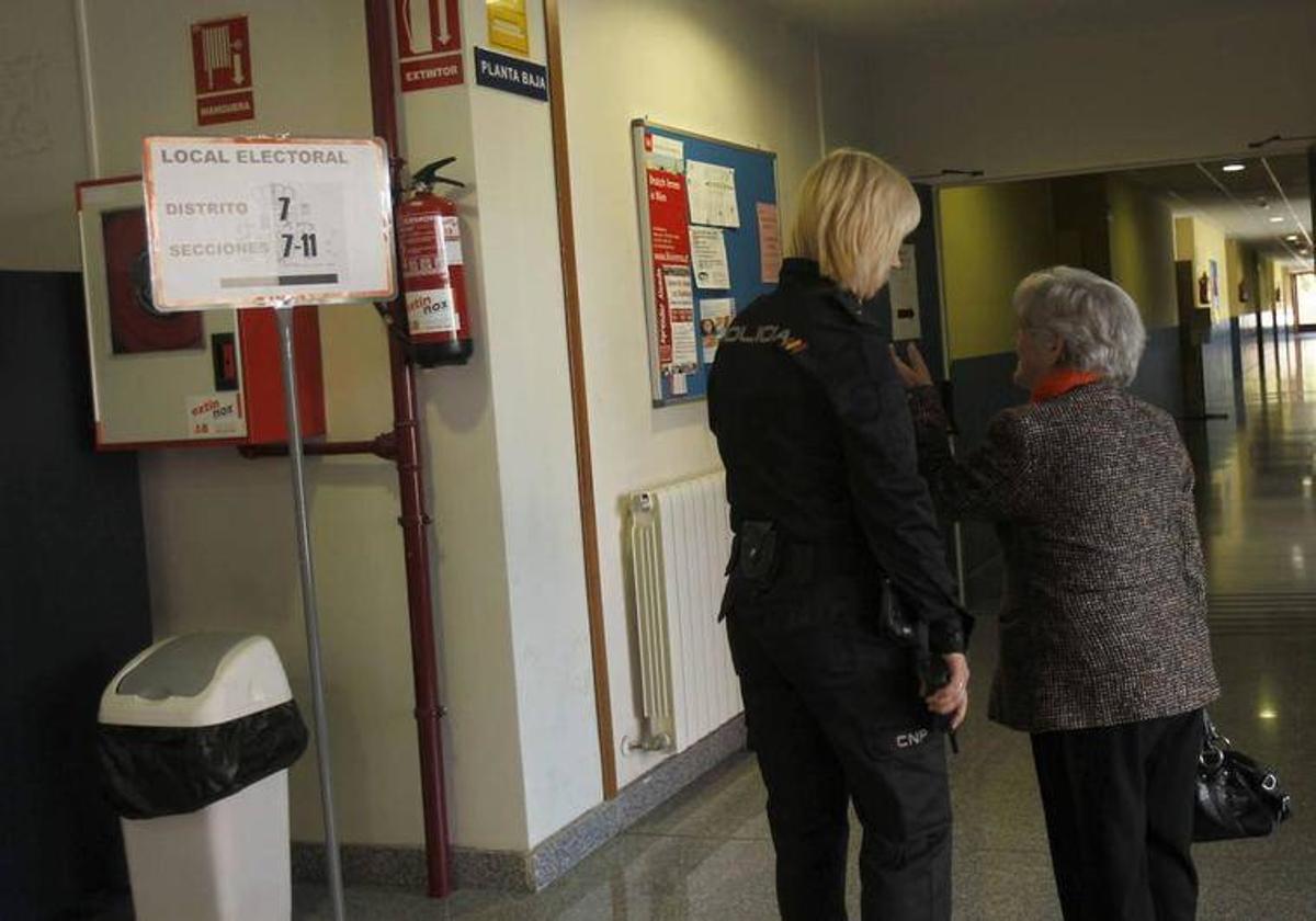 Una agente de Policía Nacional atiende a una persona en un colegio electoral