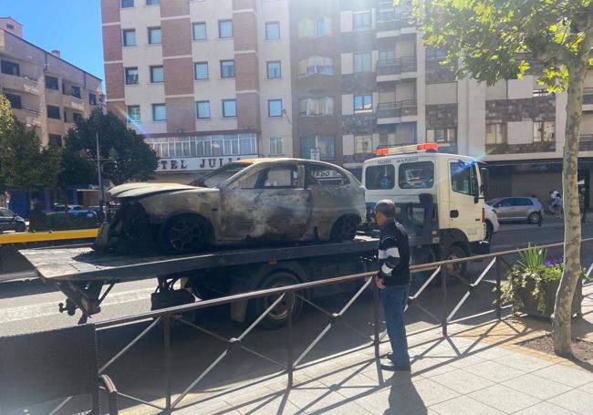 La grúa llevándose uno de los vehículos calcinados en Aranda.