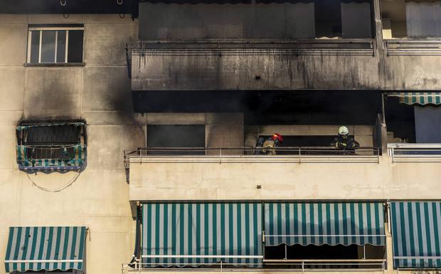 Imagen principal - En la imagen superior, los bomberos en la terraza del piso donde comenzó el fuego; debajo, vista de la fachada del edificio de Fuengirola en la que se observa como el incendio terminó dañando parte de los pisos superiores; por último, varios policías vigilan los acceso al lugar de los hechos.