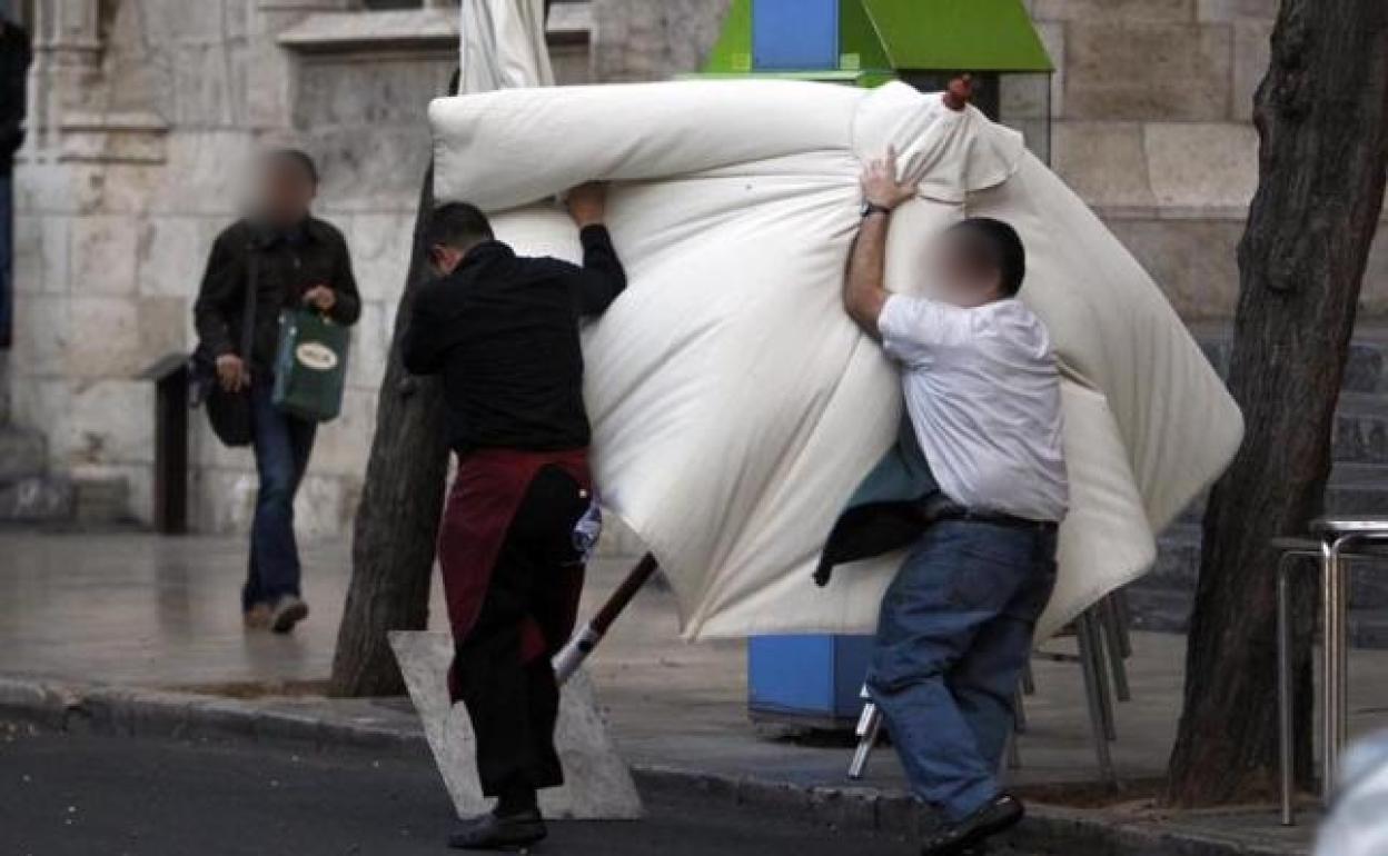 Dos trabajadores luchan contra el viento para recoger una sombrilla en Burgos 