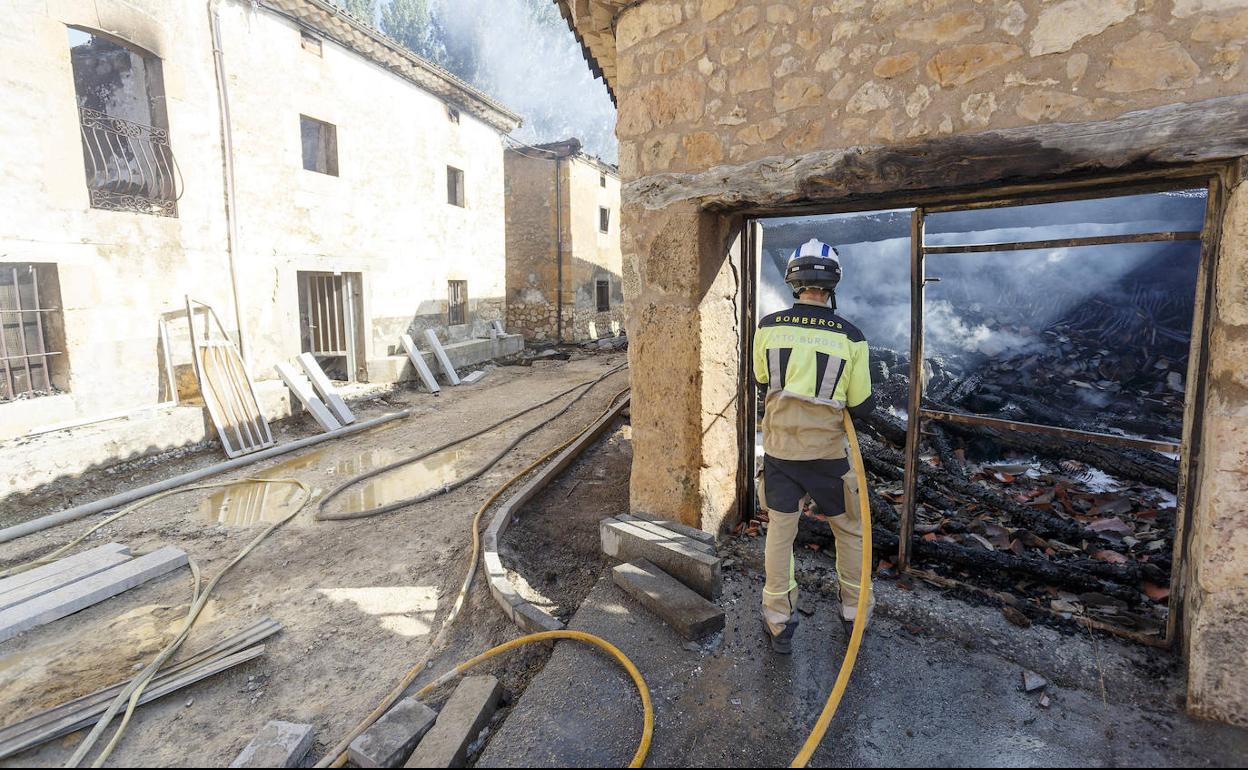 Un bombero echa agua al interior de una vivienda de Santibáñez del Val el día después de que se declarase el incendio forestal.