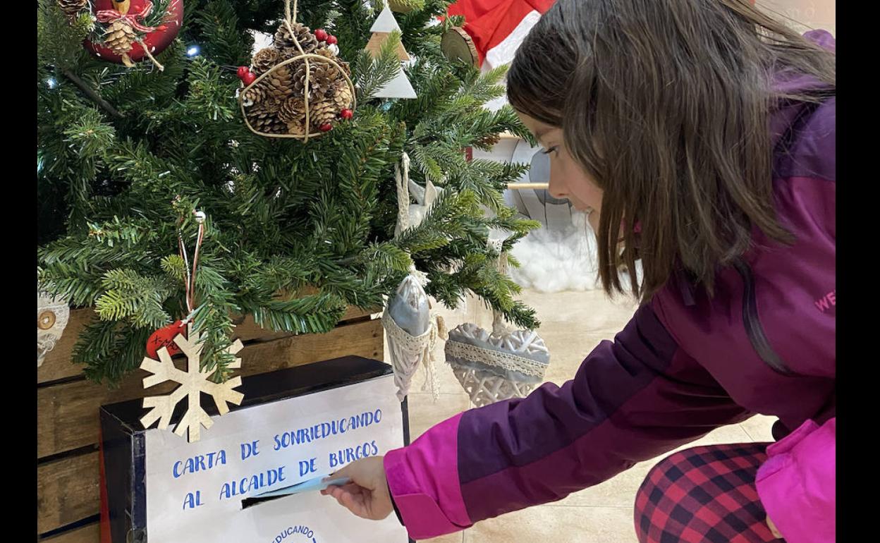 Una alumna introduce en el buzón su carta para el alcalde.