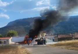 El camión en llamas mientras un hombre intenta sofocar el fuego en Barbadillo del Mercado.