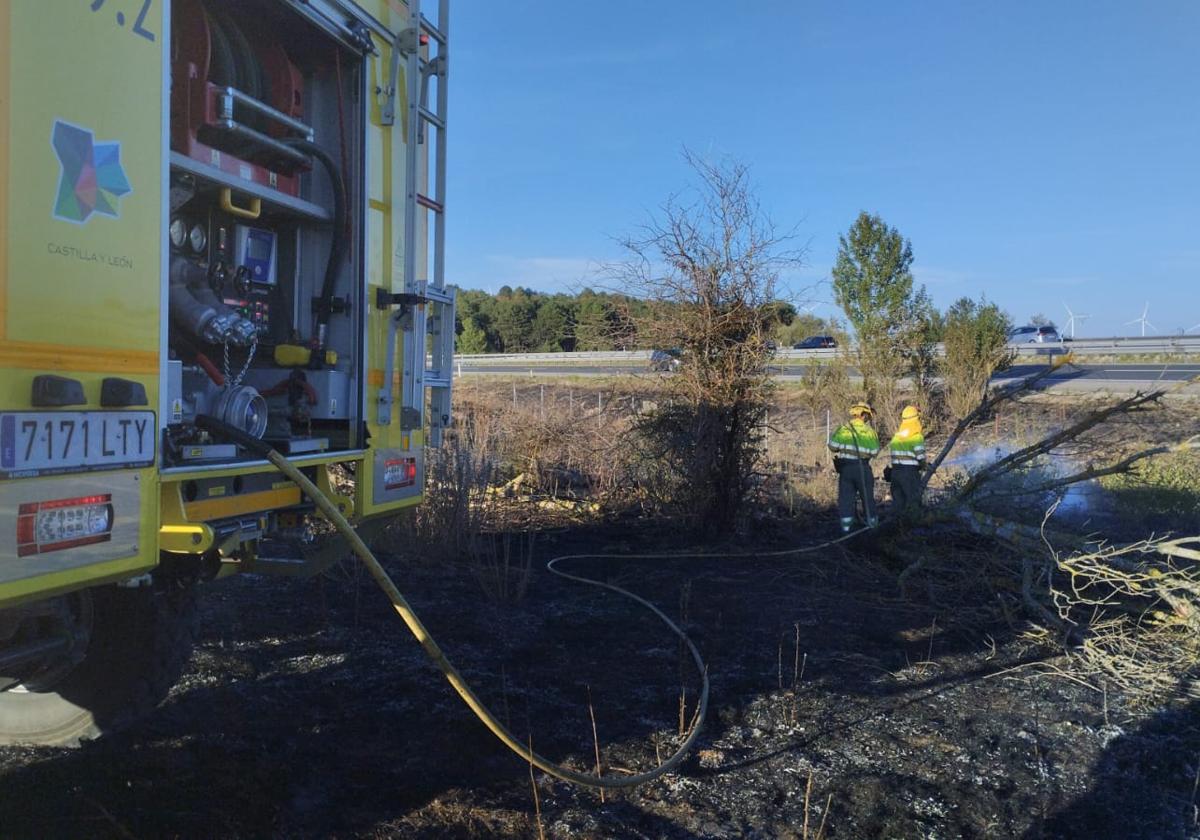 Medios de extinción trabajando en el fuego cercano a la carretera.