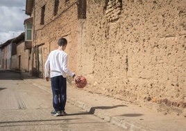 Un niño juega solo en un pueblo.