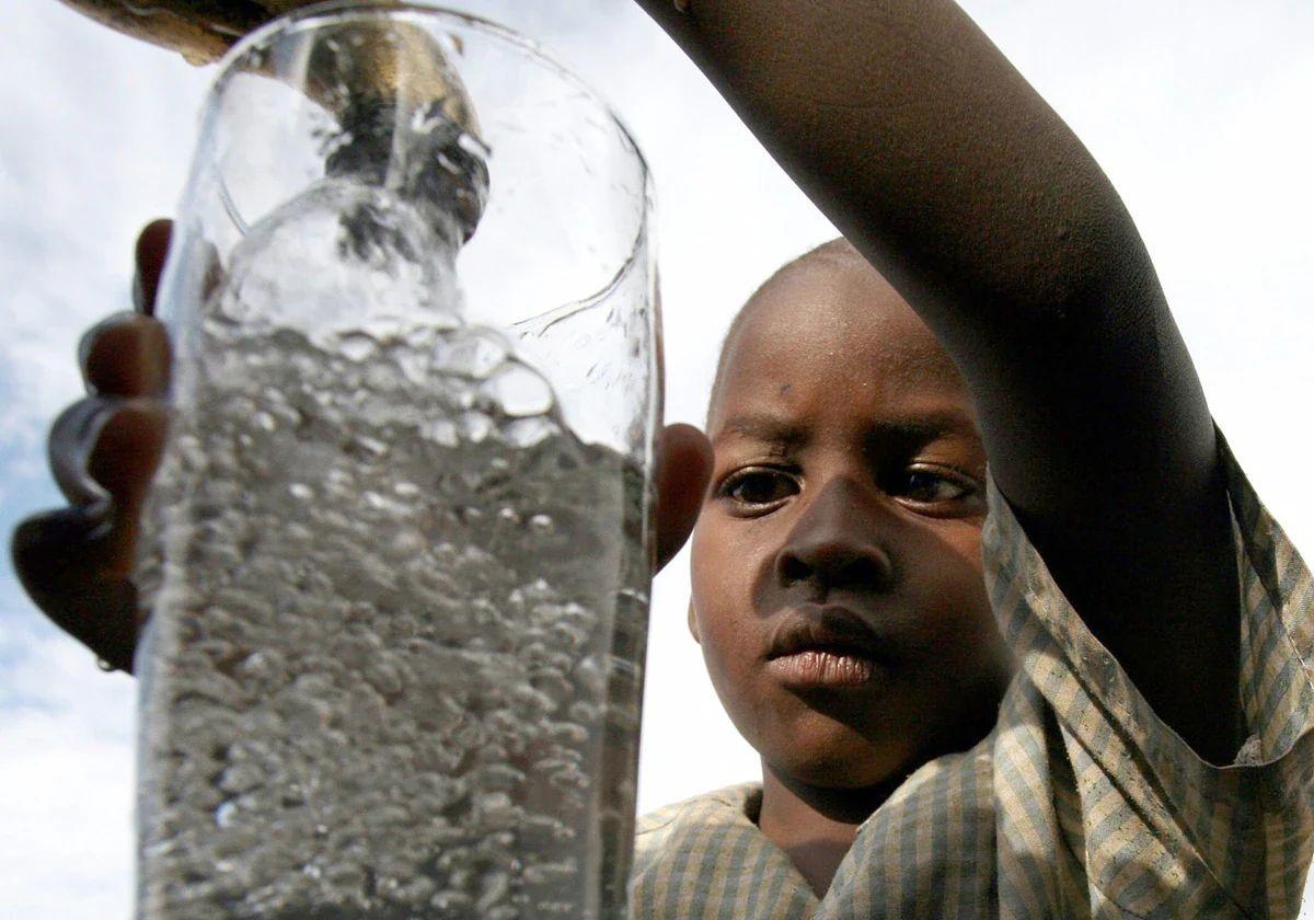 Un niño sudafricano coge agua de un grifo comunitario en el pueblo de Soweto