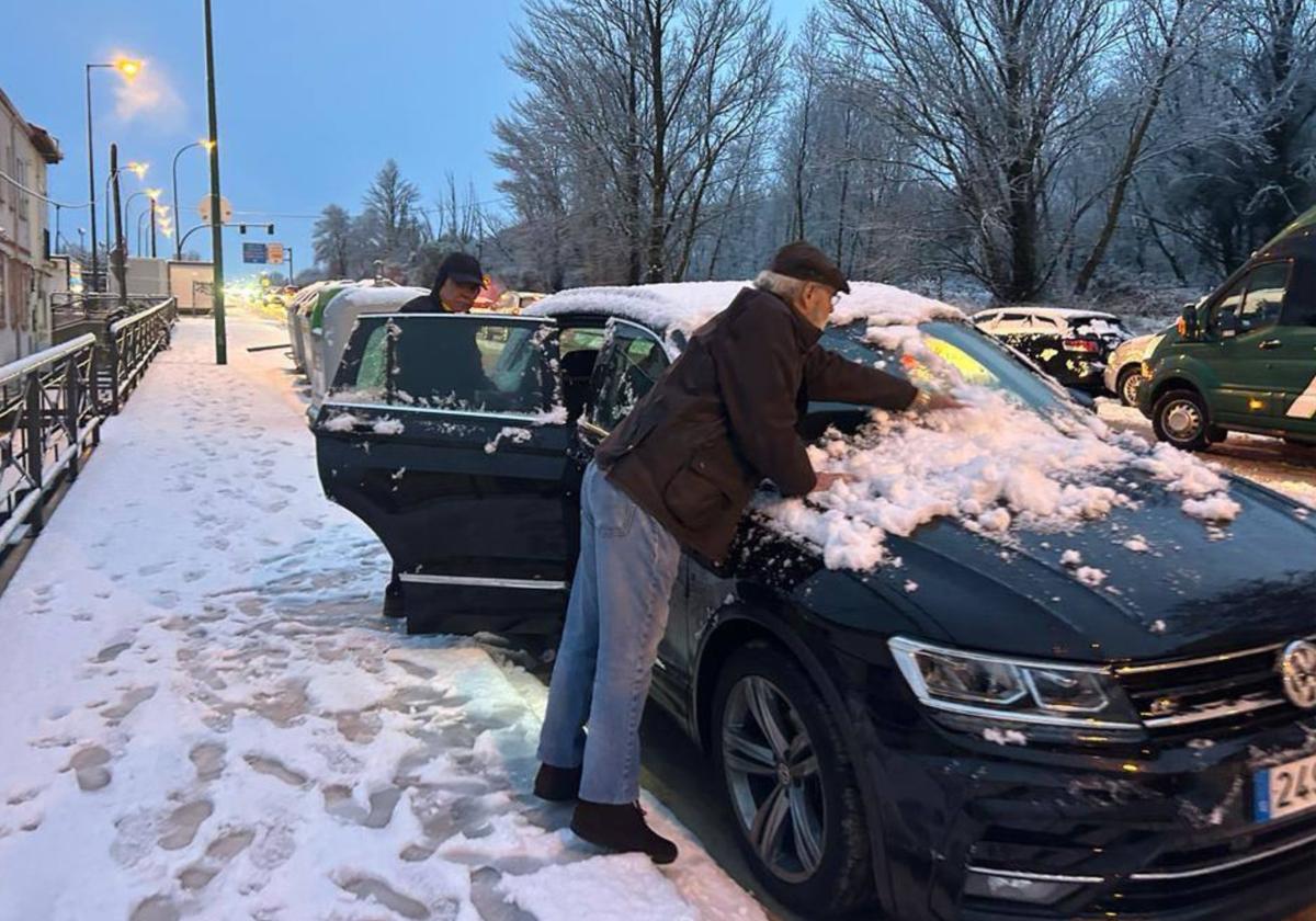 Vecinos de Burgos retiran nieve de su coche tras una nevada en 2024.