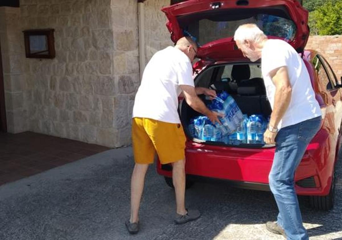 Imagen principal - Dos vecinos recogían agua embotellada de la Casa del Concejo cuando no podían consumir la del grifo. 
