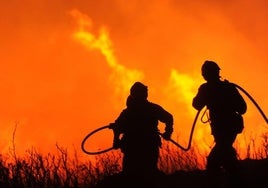 Imagen de archivo de dos bomberos forestales mientras tratan de frenar un incendio.