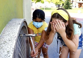 Dos niñas se refrescan en una fuente de Miranda por el calor.