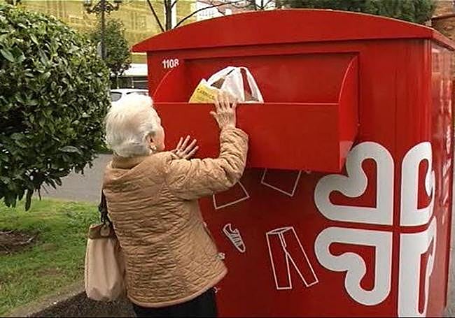 Una mujer usa el característico contenedor rojo de Cáritas.