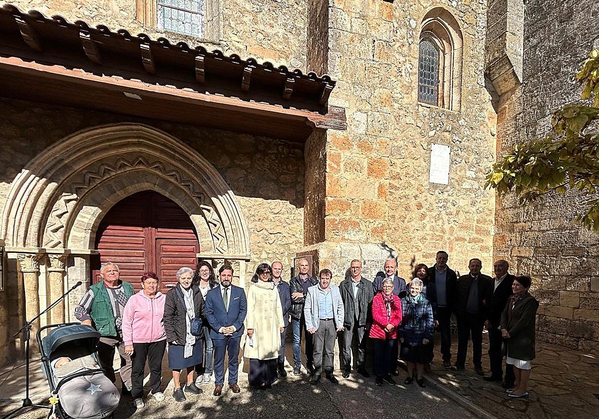 Autoridades y vecinos del pueblo junto a la placa conmemorativa de la restauración de la iglesia.