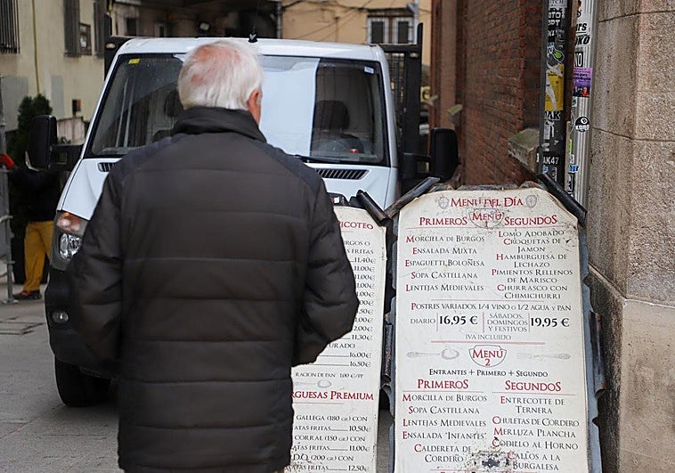 Un hombre observa un cartel de un menú del día en Burgos.