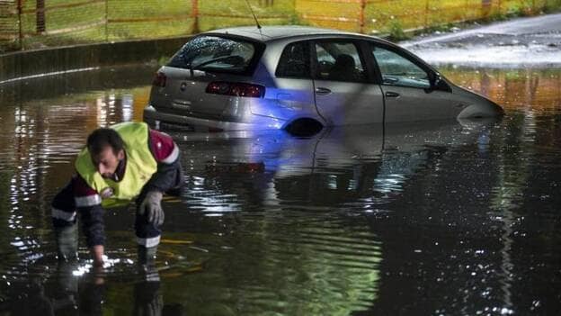 Un bombero trabaja junto a un coche semisumergido en una calle inundada tras la fuerte lluvia y el granizo caído en Roma, Italia, la noche de ayer, 21 de octubre de 2018./ Efe.