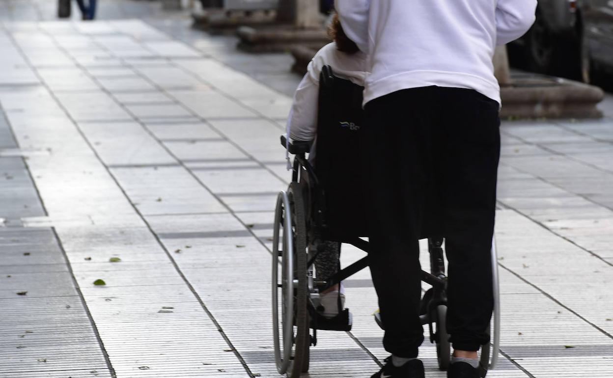 Imagen de un cuidador paseando a un dependiente