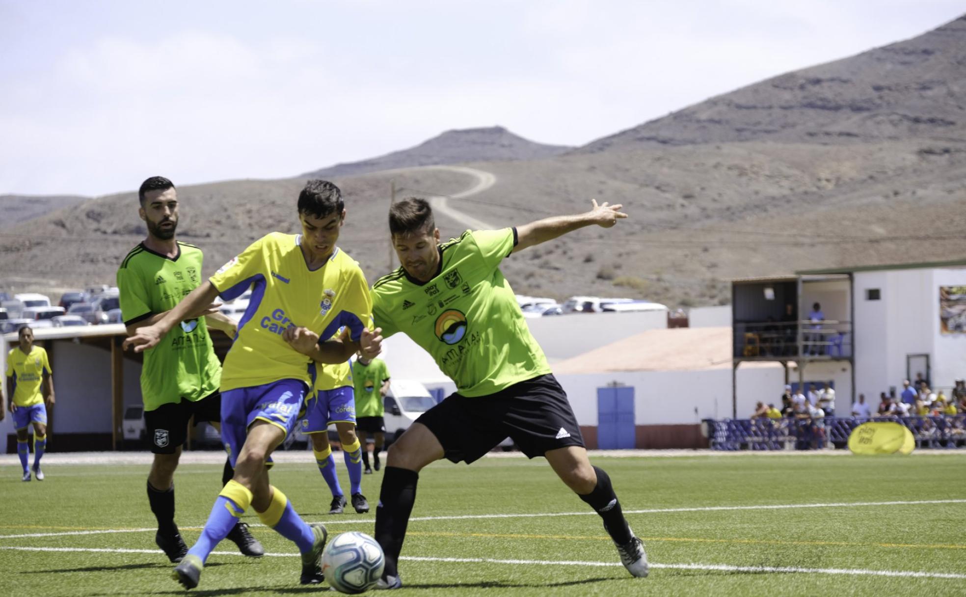 Pedri, entre dos adversarios, en el amistoso que jugó con la UD ante el Gran Tarajal hace justo un año. Fue su debut.
