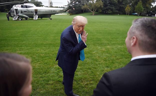Trump simula hacer una confidencia a los periodistas tras descender de un helicóptero militar en los jardines de la Casa Blanca.
