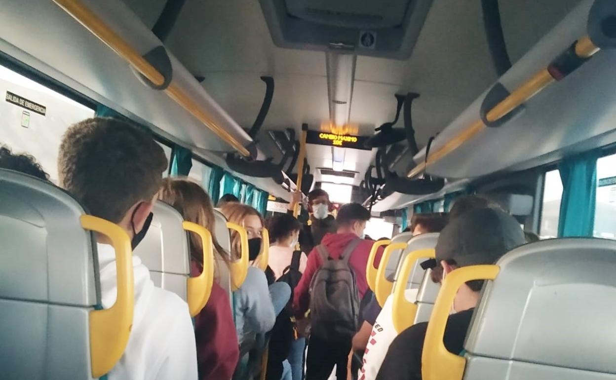 Alumnos en una guagua sureña, con viajeros de pie. 