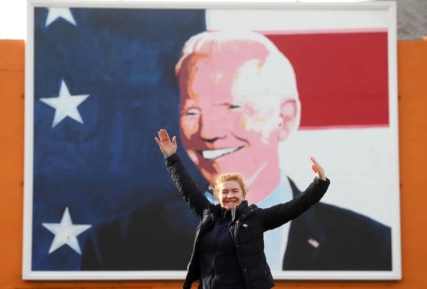 Maria Bourke, de Knockmore, posa para una fotografía debajo de un mural del candidato presidencial estadounidense Joe Biden en su casa ancestral de Ballina, donde visitó en junio de 2016 como vicepresidente de Estados Unidos.