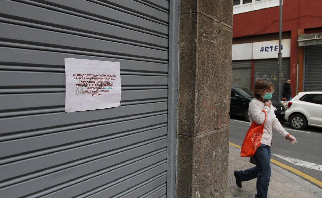 Una mujer pasa delante de una peluquería cerrada en Bilbao.