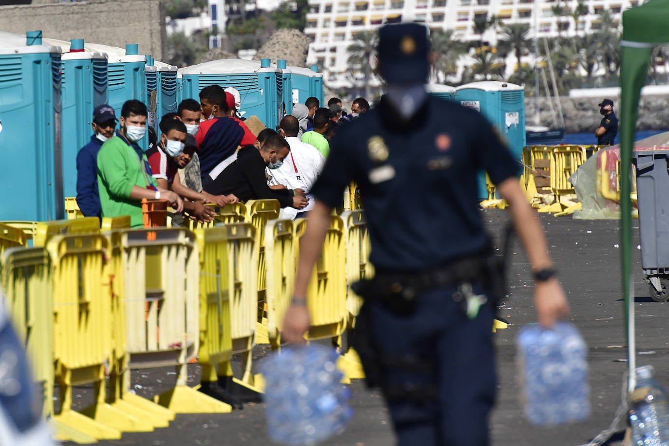 Un Policía en Arguineguín transporta garrafas de agua. 