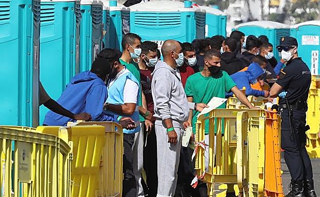 Varios inmigrantes llegados la pasada madrugada esperan este miércoles en el muelle de Arguineguín (Gran Canaria) a que les tomen las huellas dactilares y la filiación